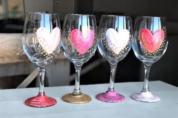 four wine glasses with pink, white and red hearts pained on them
