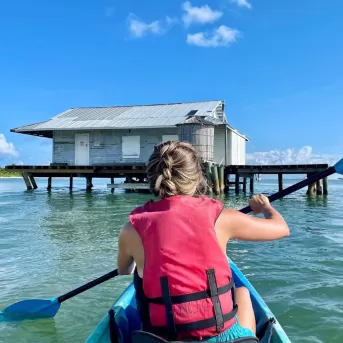 A woman in a pink shirt paddling a blue kayak